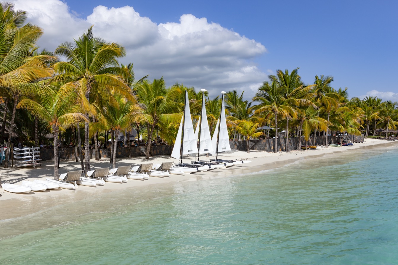 Plage de Trou aux Biches, Mauricien avec palmiers, catamarans et sable blanc.