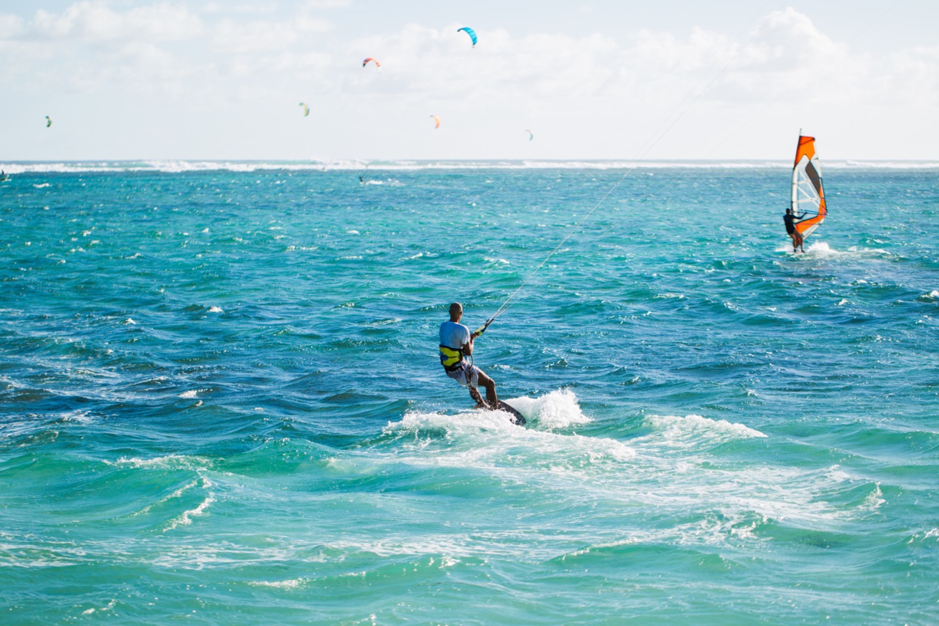 Kitesurfers en action à Le Morne, plage de l'île Maurice, mer turquoise et ciel clair.