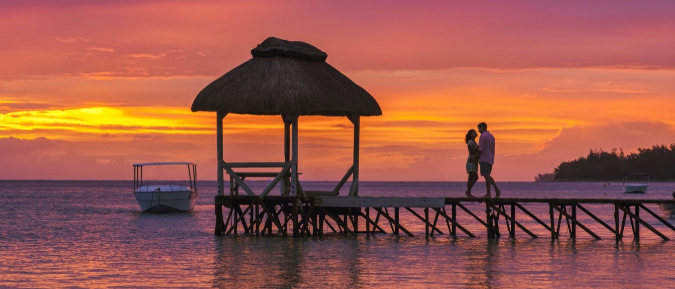 Couple sur un ponton au bord de l'eau à l'heure dorée à Maurice