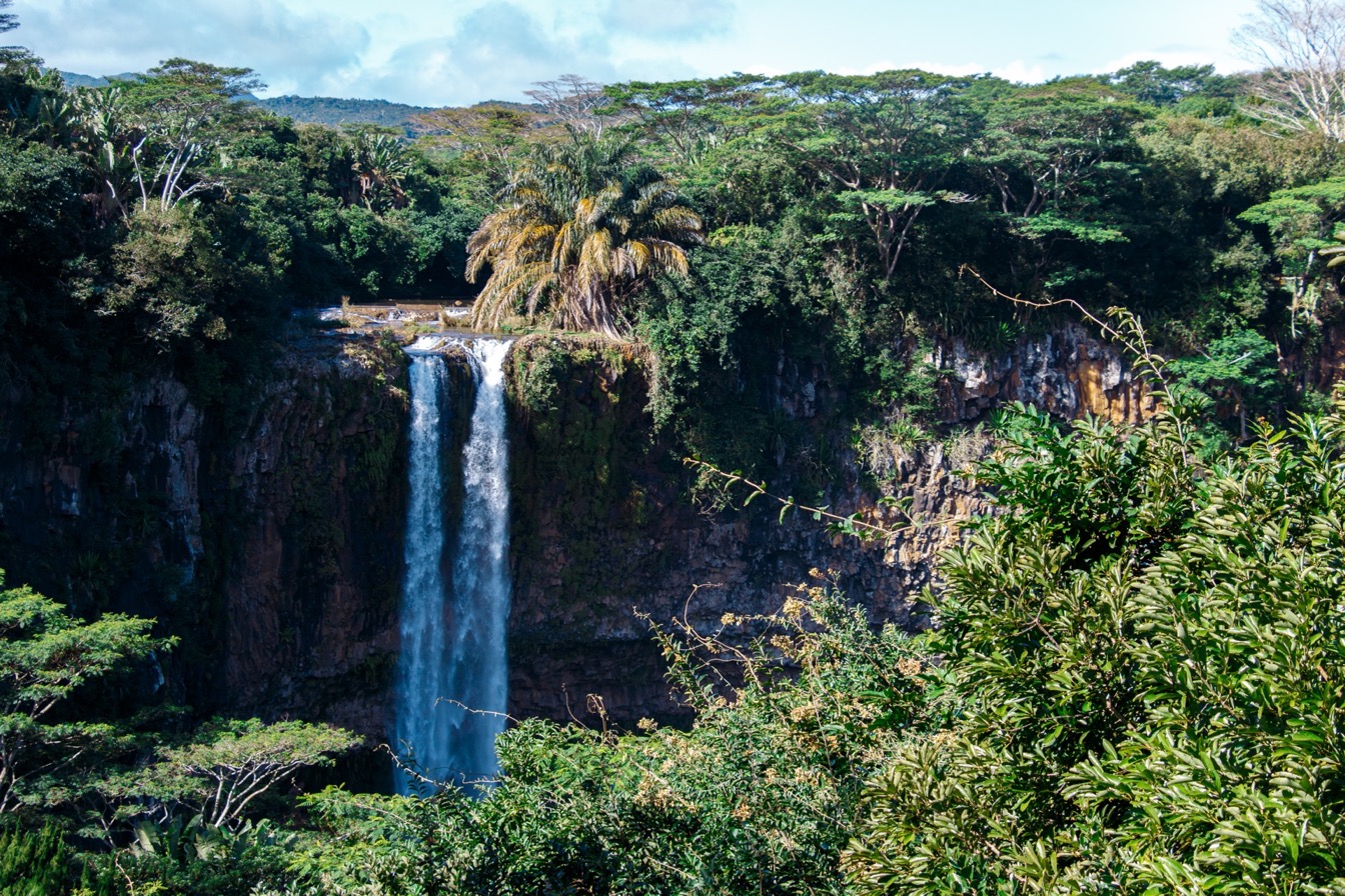 Cascades sur l'île Maurice, entourées de végétation luxuriante, avec un grand bassin d'eau en bas.