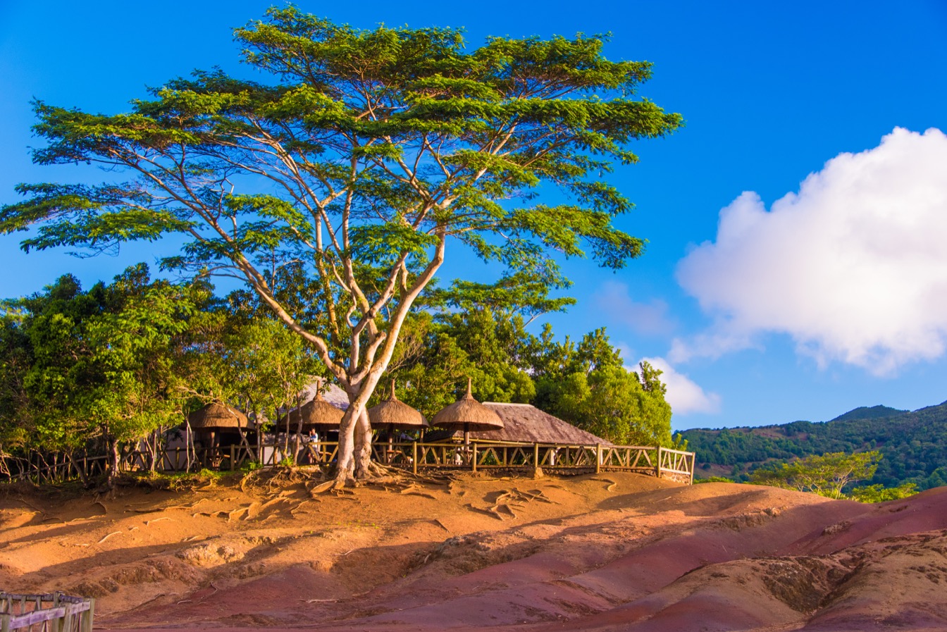 Vue de Chamarel, avec des formations de terre colorée, arbres verdoyants et cabanes en toit de chaume