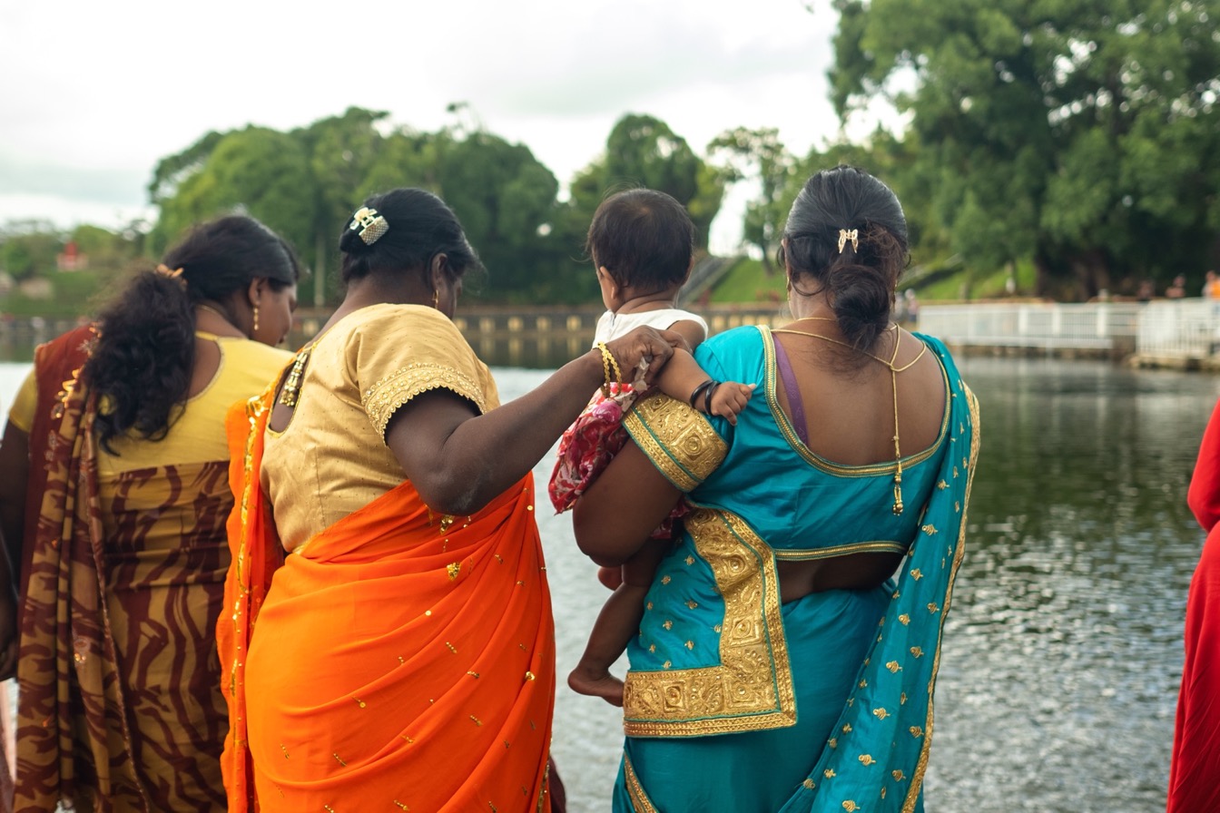 Femmes en saris colorés au bord d'un plan d'eau, célébrant des traditions à Ganga Talao, Maurice.