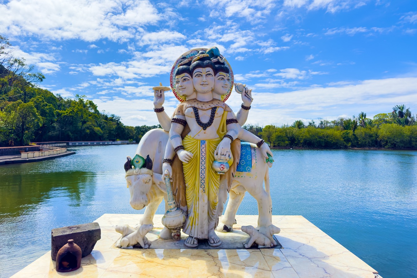 Statue de Dattatreya au temple de Grand Bassin, île Maurice, devant un lac paisible