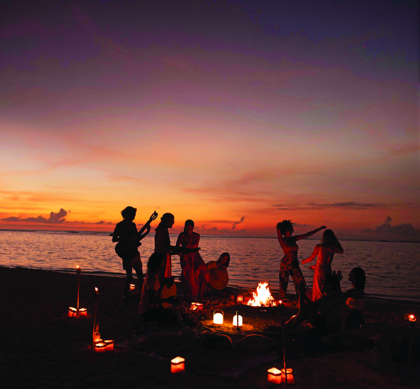 Célébration sur la plage au coucher du soleil, musique et danse autour d'un feu de camp