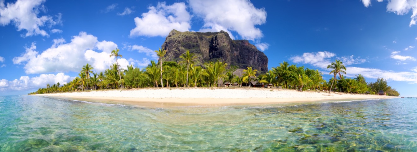 Panorama de l'île Maurice avec plage, palmiers et montagnes sous un ciel bleu