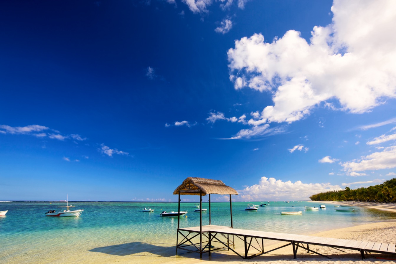 Plage à Maurice avec ciel bleu, nuages et bateaux sur l'eau cristalline