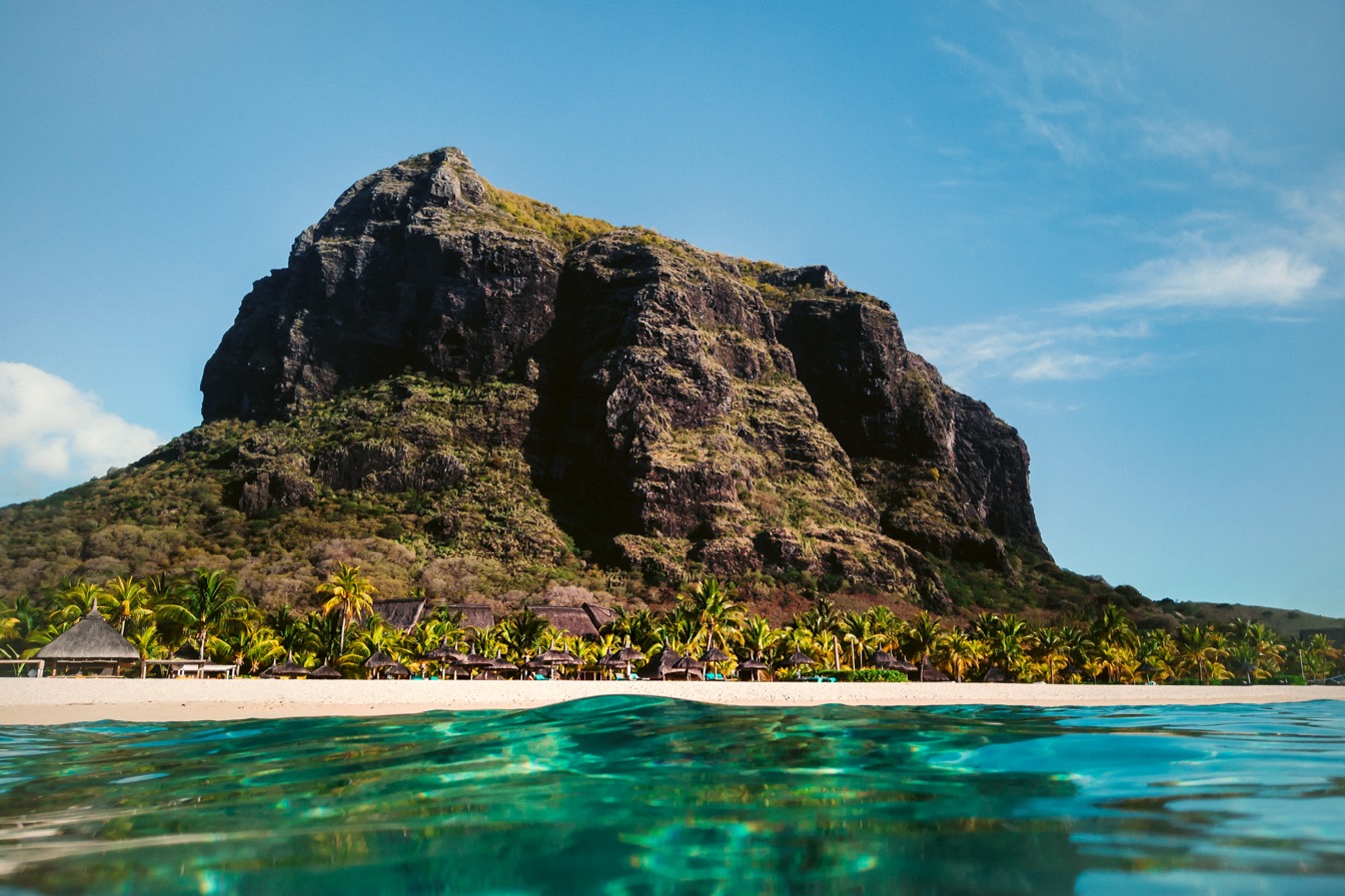 Plage de l'île Maurice avec palmiers et montagnes en arrière-plan sous un ciel bleu