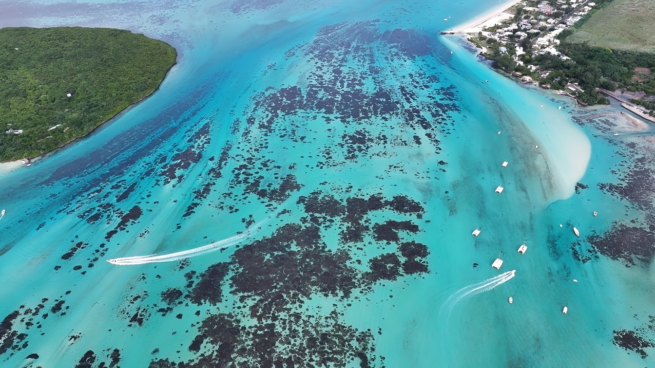 Vue aérienne de la plage de Pointe d'Esny à Maurice, avec l'eau turquoise et des bateaux.