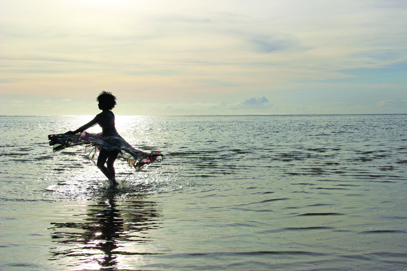 Danseuse de séga silhouettée dans l'eau, sur fond de coucher de soleil à l'île Maurice